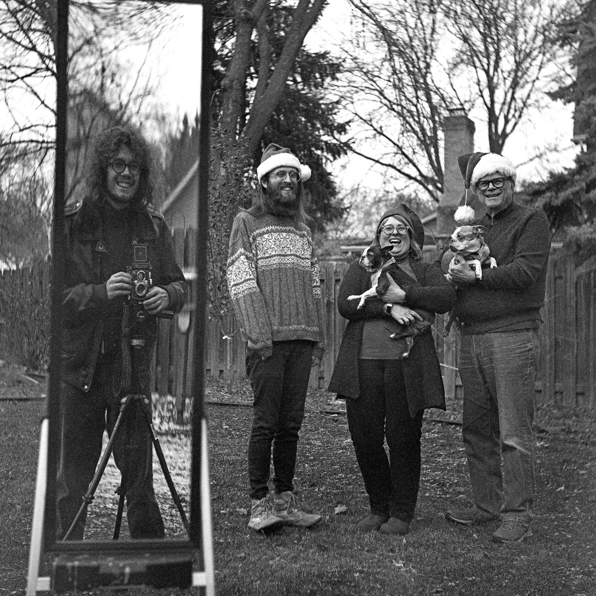 a family on a Christmas card, featuring the photographer right beside them (by way of a mirror)