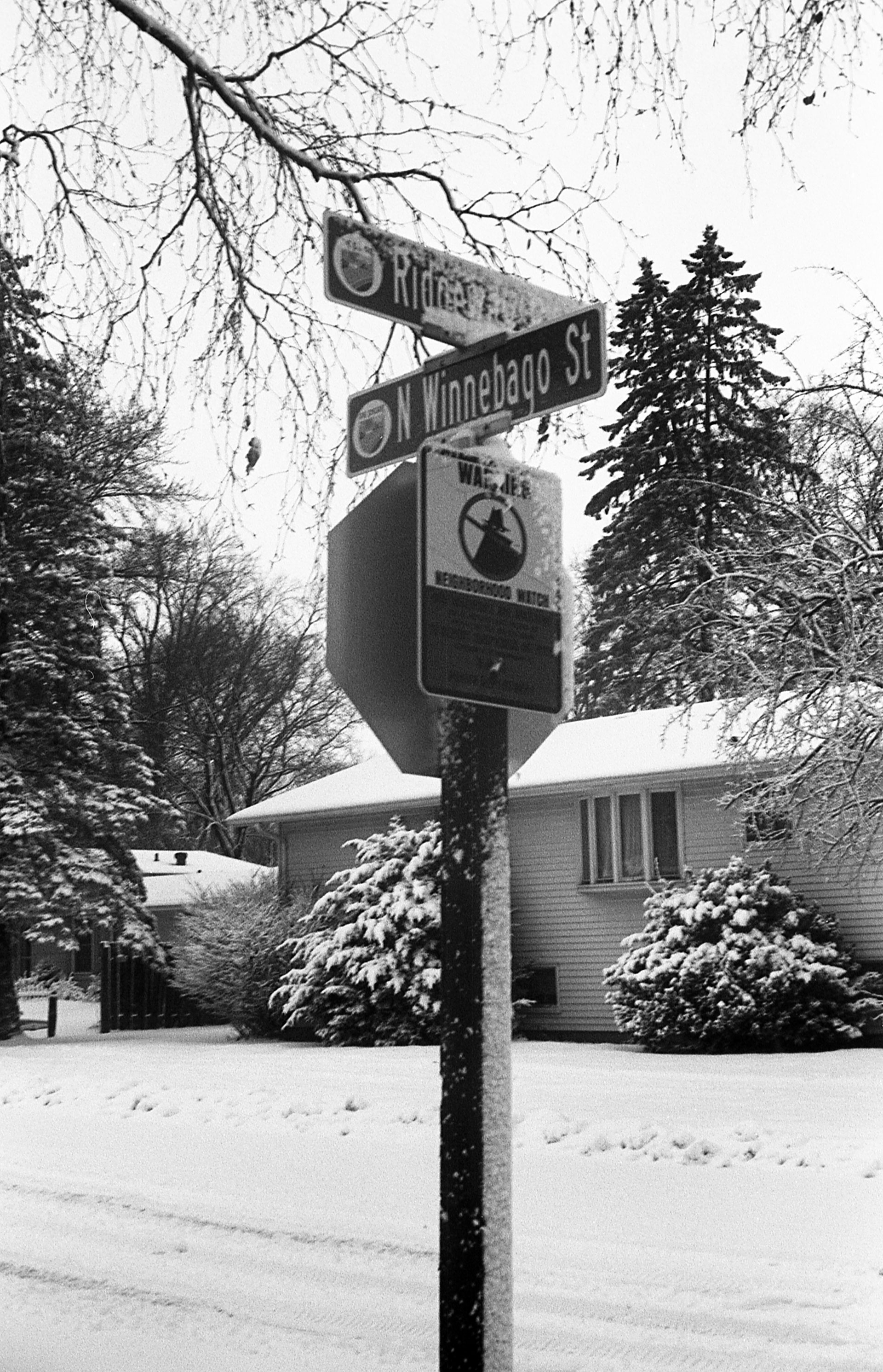 A combination street sign/stop sign, covered in snow