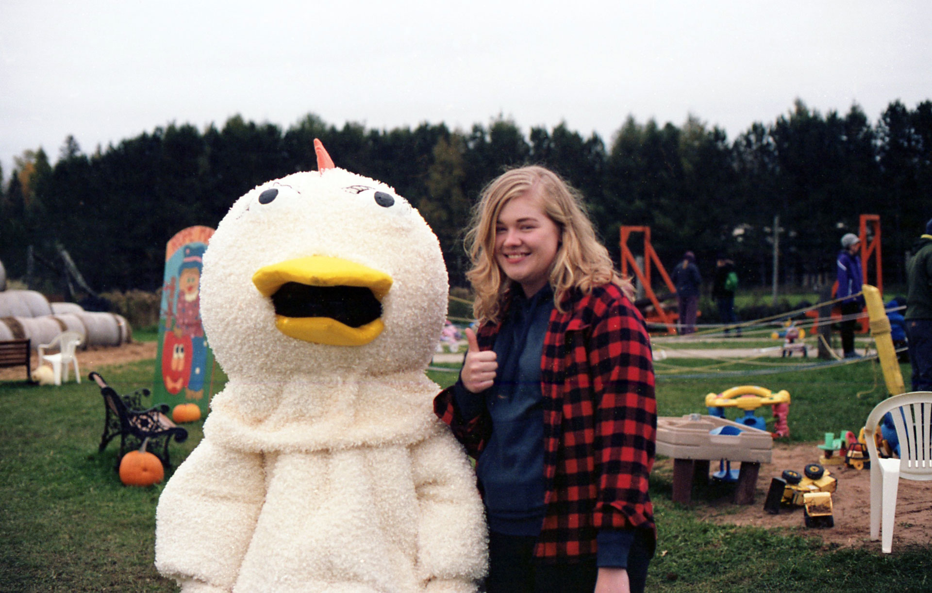 a young lady posing with a person in a chicken suit